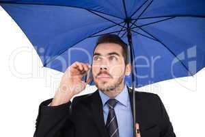 Serious businessman under umbrella phoning
