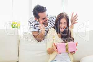 Man surprising his girlfriend with a gift on the couch