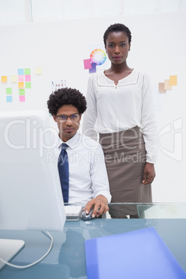 Coworkers using computer and looking at camera