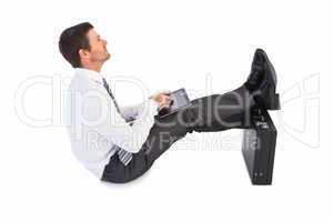 Businessman sitting with feet up while using his tablet