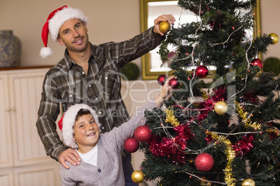 Smiling son and dad decorating the christmas tree