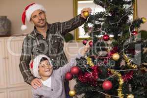 Smiling son and dad decorating the christmas tree