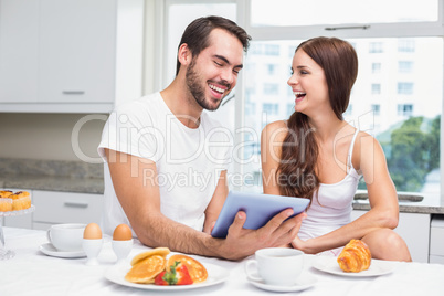 Young couple using tablet at breakfast