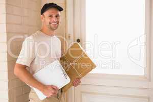 Smiling delivery man with box and clipboard