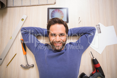 Casual man lying on floor surrounded by his diy tools