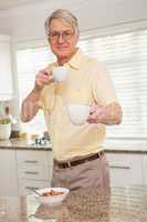 Senior man offering cup to camera