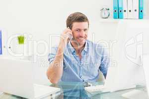 Smiling businessman on the phone at desk