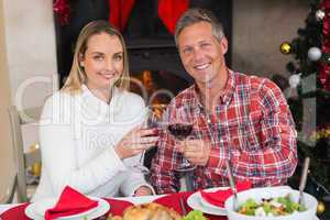 Couple toasting to the camera with red wine