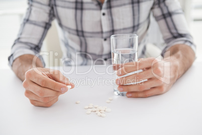 Casual businessman holding glass of water and tablet