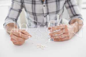 Casual businessman holding glass of water and tablet