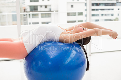 Fit brunette stretching on an exercise ball