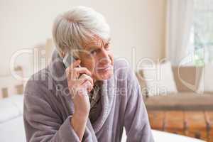 Senior man making a phone call on bed