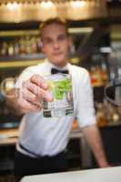 Happy bartender offering cocktail to camera