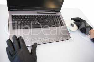 Burglar hacking and putting a cd-rom in laptop