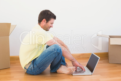 Casual man sitting on floor using laptop at home