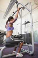 Fit woman using the weights machine for her arms