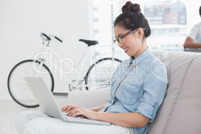 Young creative woman using laptop on couch