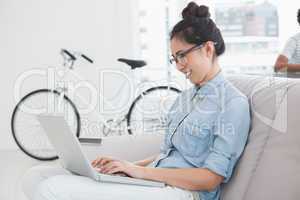 Young creative woman using laptop on couch