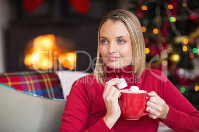 Blonde holding mug and eating marshmallow at christmas
