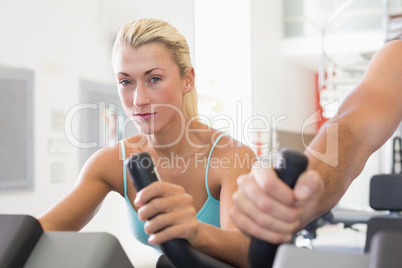 Fit couple working on exercise bikes at gym