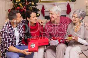 Smiling family holding present on sofa