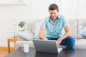 Smiling man at home on a laptop