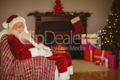 Festive santa claus sitting on couch at christmas