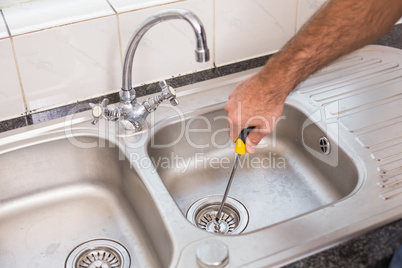 Man fixing sink with screwdriver