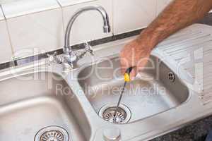 Man fixing sink with screwdriver