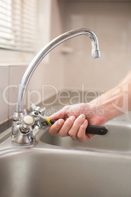 Man fixing tap with pliers