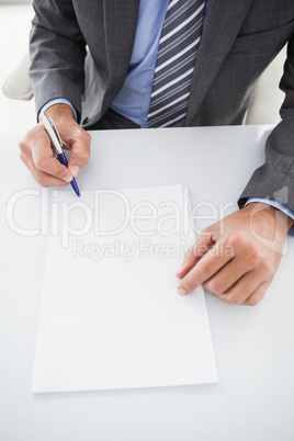 Mature businessman writing on document