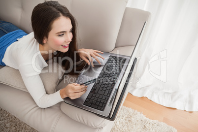 Pretty brunette shopping online on couch