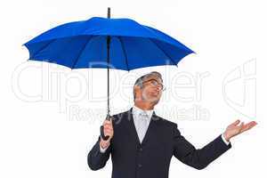 Businessman under blue umbrella with hand out