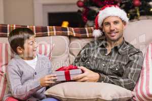 Son giving father a christmas gift on the couch