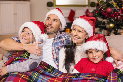 Happy family in santa hat hugging under the cover