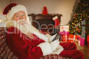 Smiling santa using smartphone at christmas