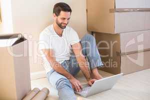 Happy man using laptop surrounded by boxes