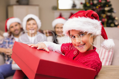 Smiling daughter holding gift with her family behind