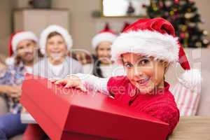 Smiling daughter holding gift with her family behind
