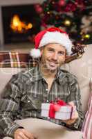 Smiling man in santa hat showing a gift