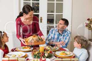 Woman serving roast turkey to her family