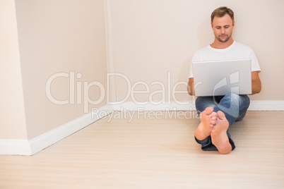 Focused man using laptop on floor