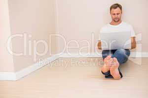 Focused man using laptop on floor