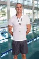 Swimming coach by pool smiling at leisure center