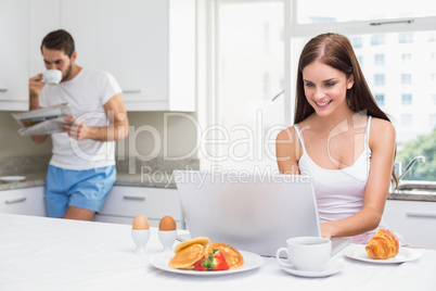 Young woman using laptop at breakfast