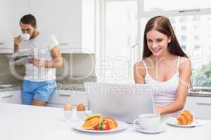 Young woman using laptop at breakfast