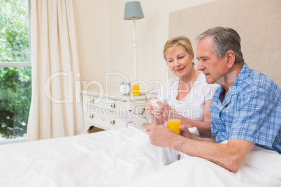 Senior couple having breakfast in bed