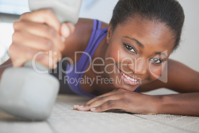 Fit woman smiling at camera holding dumbbell