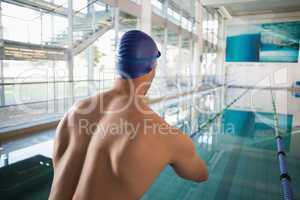 Rear view of shirtless swimmer by pool at leisure center