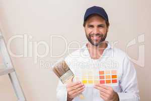 Painter holding a colour chart smiling at camera